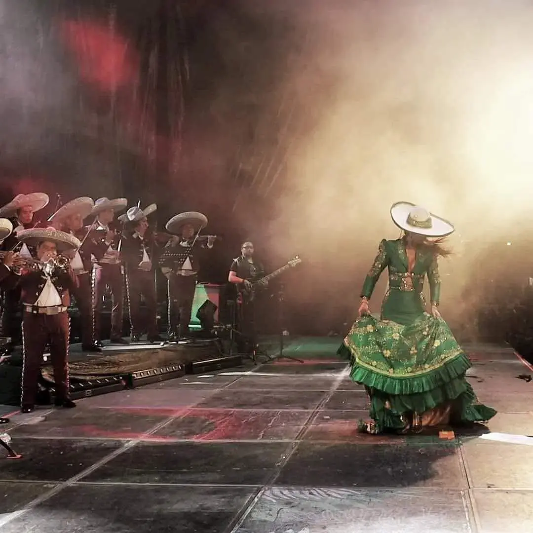 Bailarina con vestido verde acompañada por Mariachi Playense en escenario